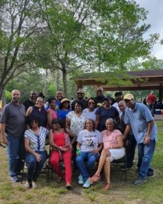 A large family group gathered on the lawn by a picnic pavilion